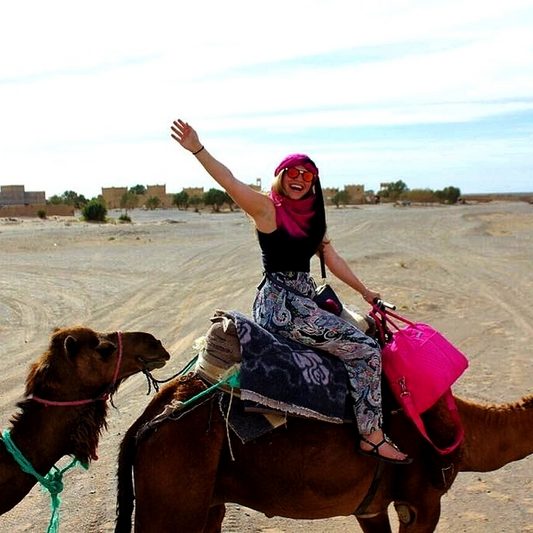 Imagen de una mujer montada en un camello en un desierto