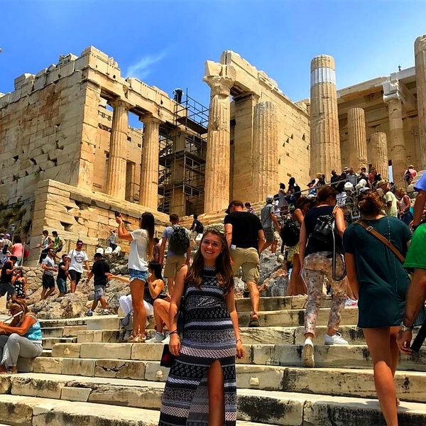 Imagen de una estudiante posando frente a Propylaea en Grecia